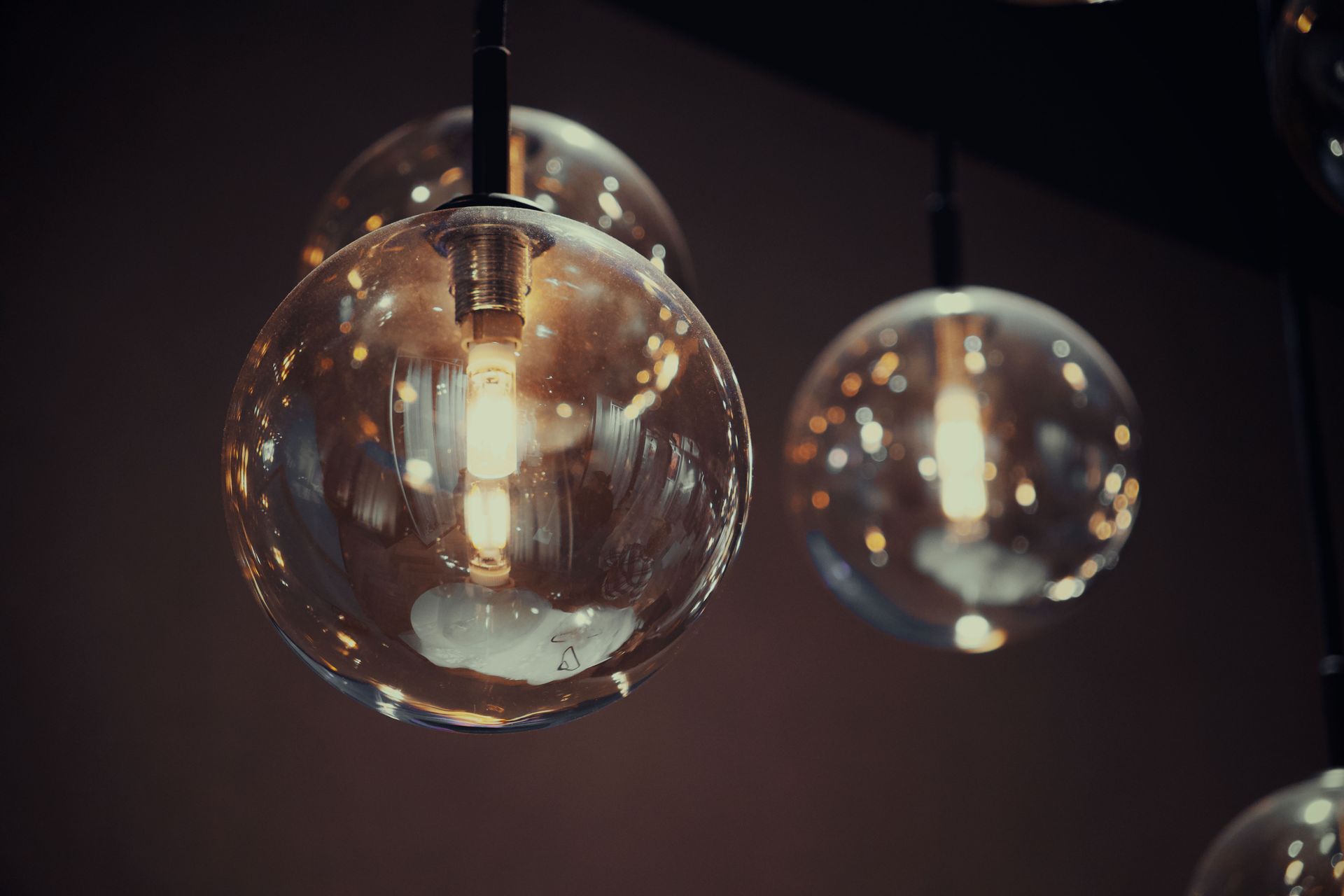Close-up of vintage Edison light bulbs in glass globes, providing a warm, moody ambiance.